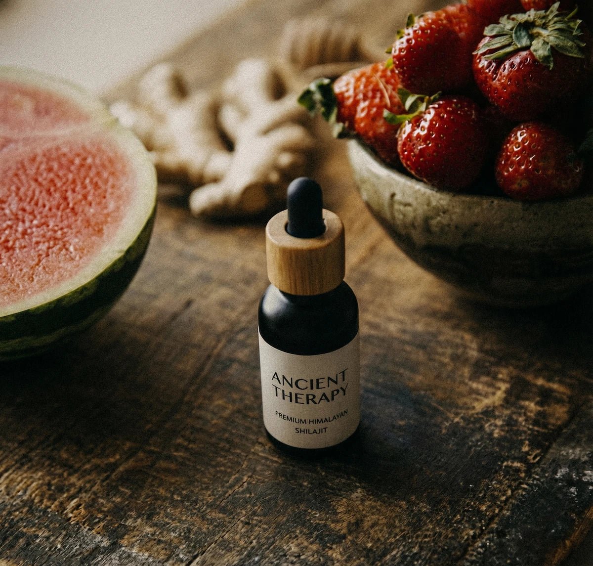Ancient Therapy's Shilajit Drops bottle on a wooden surface with fruits