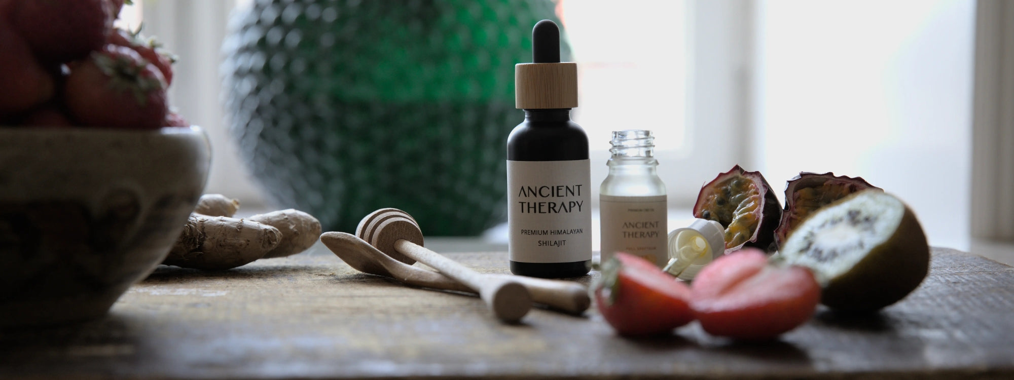 Ancient Therapy's Shilajit Drops bottle on a wooden surface with fruits