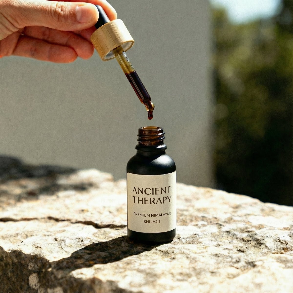 Shilajit Drops bottle on stone with dropper in natural light – Ancient Therapy, certified organic adaptogen