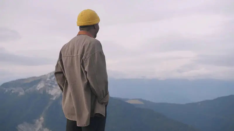 Person with a yellow beanie looking over mountain landscape